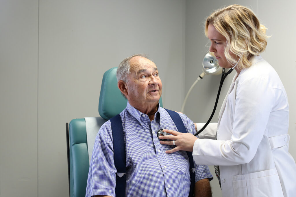 A nurse checks a patient's heartbeat with a stethoscope.