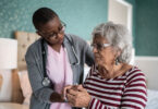 A health care provider holds the hand of an older patient.